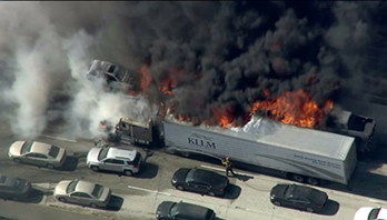 Semi truck on fire on I-15 with heavy traffic surrounding.
